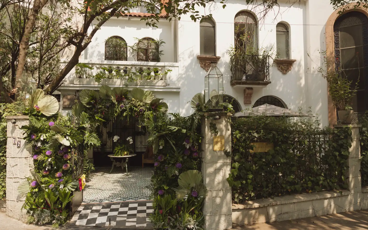 The entrance to the Polanco house decorated with palm fronds and purple flowers, over the chequered floor of the hallway