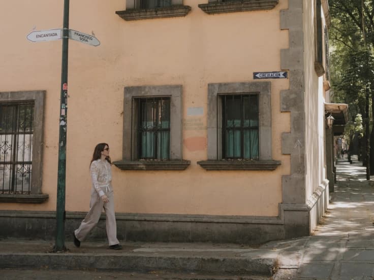 A guest walks the corner of Francisco Sosa, past the street signs and the house's peach-coloured facade