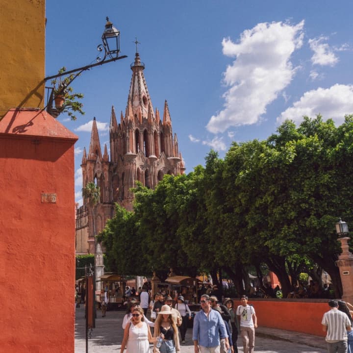 La Parroquia's tower over the streets of San Miguel de Allende, with tourists walking by